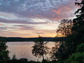Sjö och himmel med rödtonade moln i solnedgången